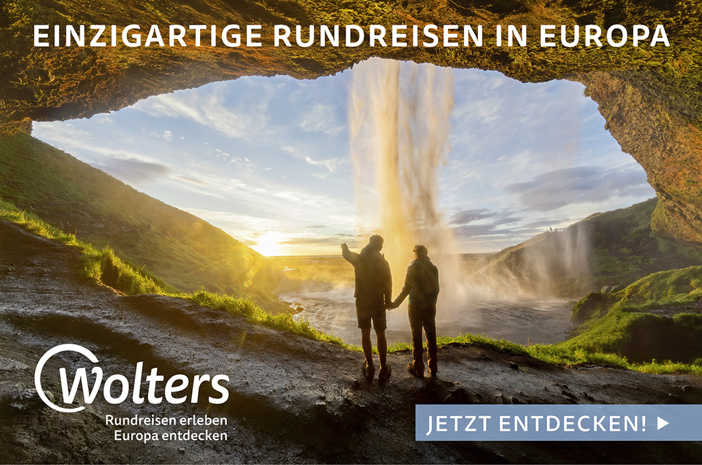Werbebanner von Wolters: Zwei Personen stehen in einer Felshöhle und blicken auf einen dramatischen Wasserfall bei Sonnenuntergang. Text: Einzigartige Rundreisen in Europa. Jetzt entdecken!